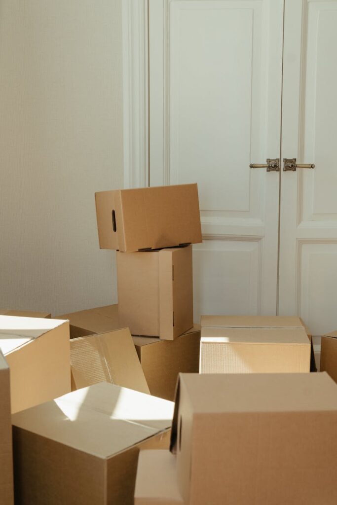 Stack of cardboard boxes by a white wooden door, perfect representation of moving day readiness. Haushaltsaufl&ouml;sung bei ks-haushaltsaufloesung.de